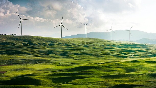 Bild von einem Windpark auf einem grünen Hügel